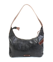 The Seemly shoulder bag by Bed|Stü features a black leather exterior with a brown strap, a zippered top opening, and a stylish brown accent detail on one side. Designed in a compact silhouette that's perfect for everyday styling, this bag is photographed against a white background.