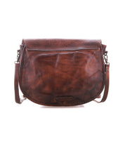The Sequoia EM by Bed|Stü is a brown leather crossbody satchel bag, crafted from vegetable-tanned leather with a subtle embossed pattern on the flap. Featuring a curved saddle bag silhouette and an adjustable shoulder strap, this stylish accessory is displayed against a white background.