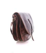 The Sequoia EM crossbody bag by Bed|Stü is crafted from vegetable-tanned brown leather with an embossed pattern, featuring a flap cover and adjustable strap. Shown on a white background, this saddle bag blends timeless style with durable functionality.