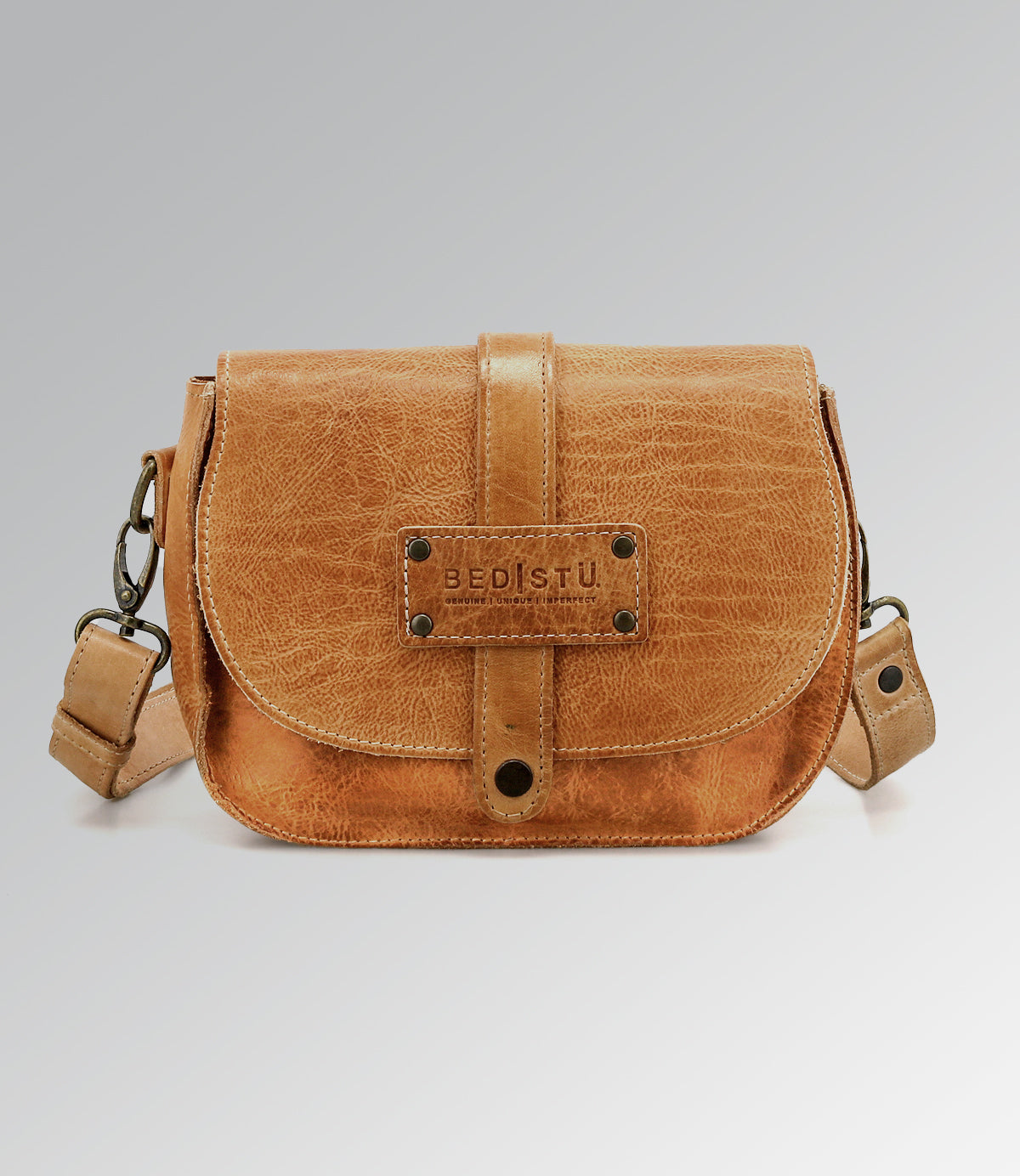 Light brown Studio Shoreline II Body crossbody bag by Bed|Stü, featuring a front flap, metal hardware, and a signature "Bed|Stü" logo patch on the front, offering a distinctive design that stands out against a plain gray background.
