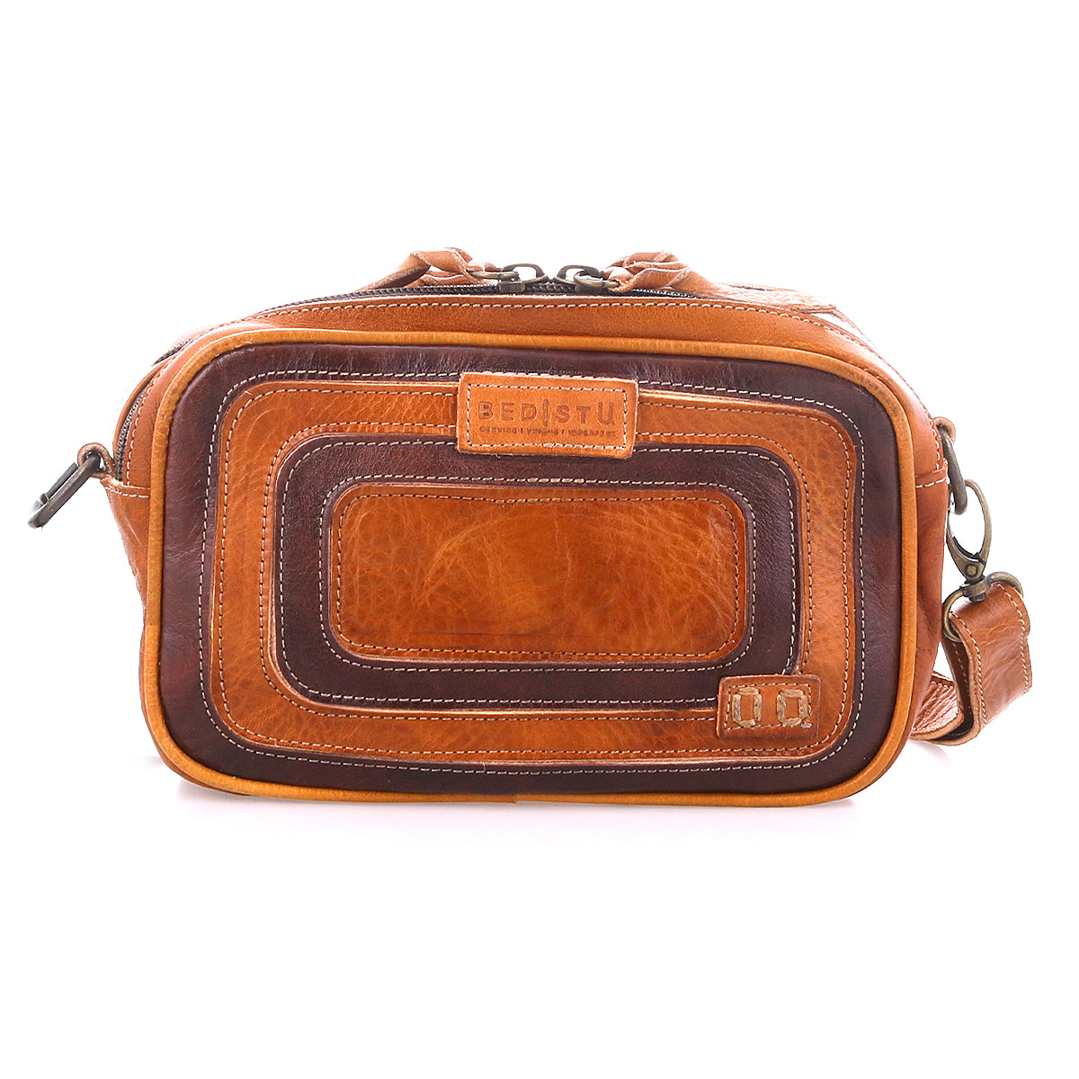 Introducing Shy by Bed|Stü—a rectangular brown leather crossbody bag showcasing a textured, layered front design. It features a top zipper closure, an adjustable shoulder strap for comfortable wear, and dual pockets that offer easy access and efficient organization of your essentials. The Bed|Stü brand name is displayed on a front leather patch.