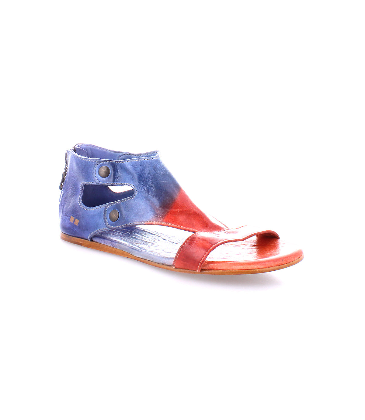 The Bed|Stü Soto is a flat cutout leather sandal featuring an open toe, two ankle buttons, and a striking red and blue color gradient. Designed for everyday exploring, it includes a cushioned footbed for added comfort. Shown on a white background.