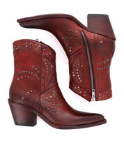 A pair of Bed|Stü Sposa ankle boots crafted from brown vegetable-tanned leather, featuring decorative studs, side zippers, and stacked heels; one Italian-designed boot is displayed upright while the other rests on its side.