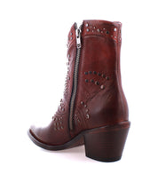 Introducing Sposa by Bed|Stü—a brown Italian ankle boot crafted from rich vegetable-tanned leather. Featuring decorative metal studs, a side zipper, and a stacked heel, this pointed toe bootie is displayed from a rear-side angle against a white background.