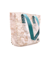 The Stevie by Bed|Stü is a beige leather tote bag featuring a marbled pattern, teal double handles, white side stitching, and a small Bed|Stü branded patch near the bottom—perfect for your everyday carry.