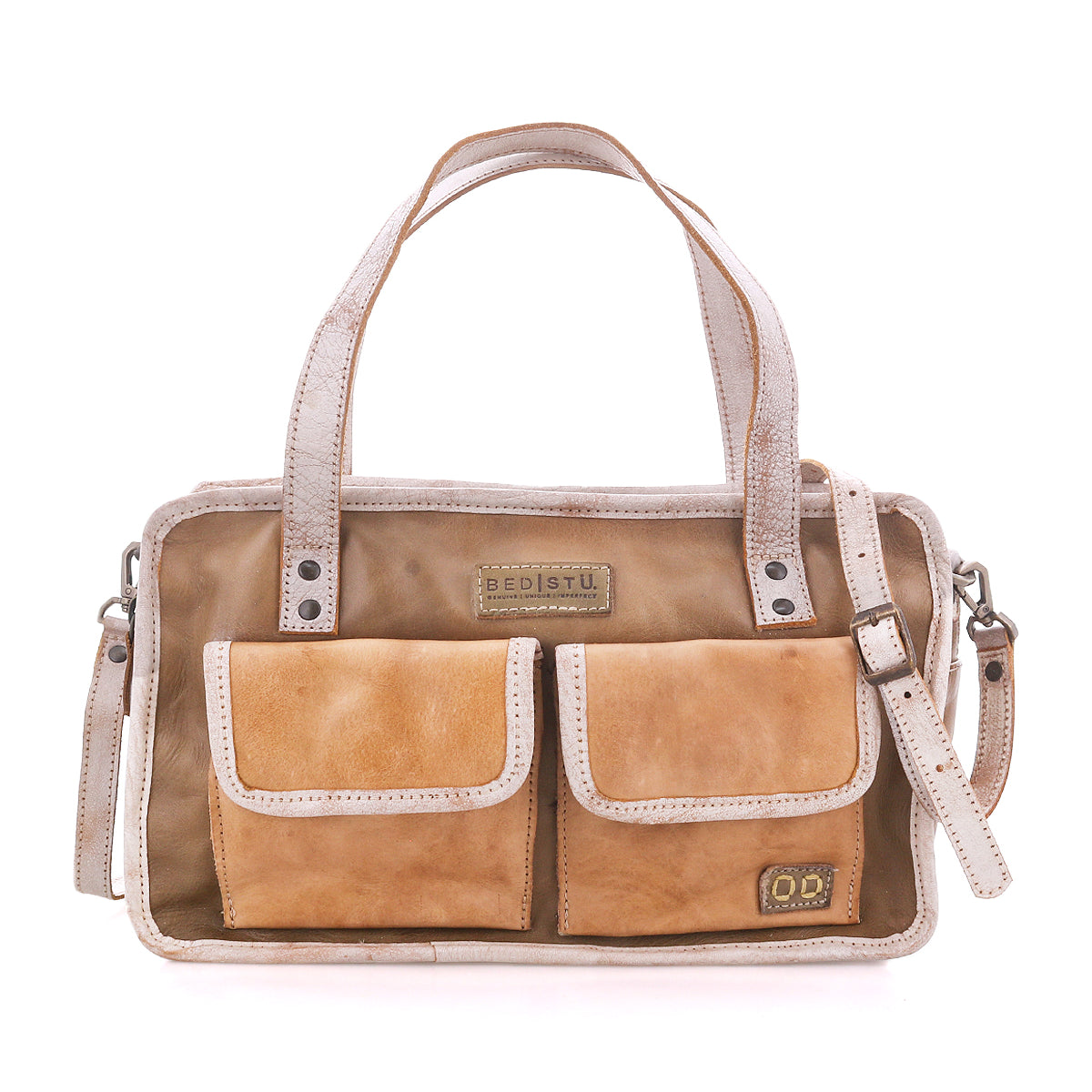 The “Stuffy” handbag by Bed|Stü is crafted in tan leather with a structured silhouette, featuring two front pockets, dual top handles, a removable shoulder strap, decorative stitching, and branded labels displayed on the front for a preppy look.