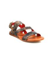 The Bed|Stü Superb sandal features brown leather with a flat sole, adjustable ankle strap, buckle closure, and open-toe design. Its worn leather texture adds character, making it ideal for everyday wear. The Superb sandal is shown angled on a white background.