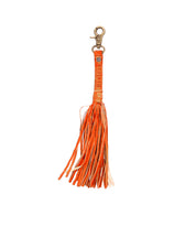 The Tassel Clip by Bed|Stü is an orange leather keychain with a metal clasp, designed with multiple thin strips and an embossed label near the top—ideal as a chic keychain charm or tasteful bag accessory.