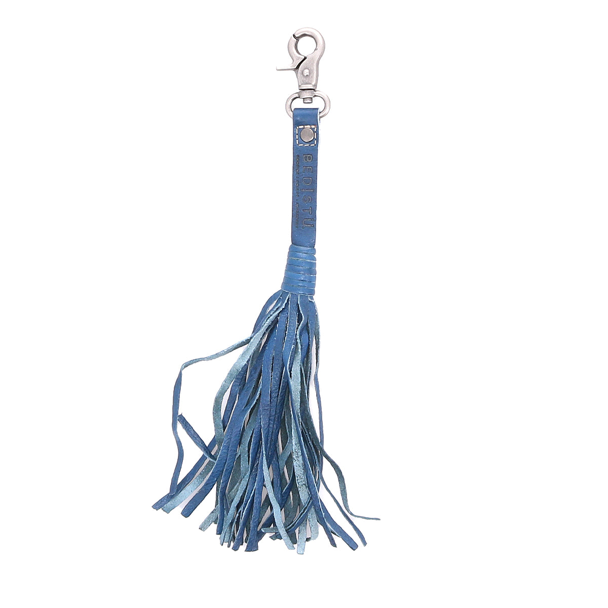 The Bed|Stü Tassel Clip is a blue leather keychain featuring multiple thin strips and a silver clasp, serving as both a stylish keychain charm and a chic bag accessory.