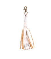 The Bed|Stü Tassel Clip is a tan and white leather keychain with a metal clasp, shown against a white background, making it a stylish bag accessory or charm.