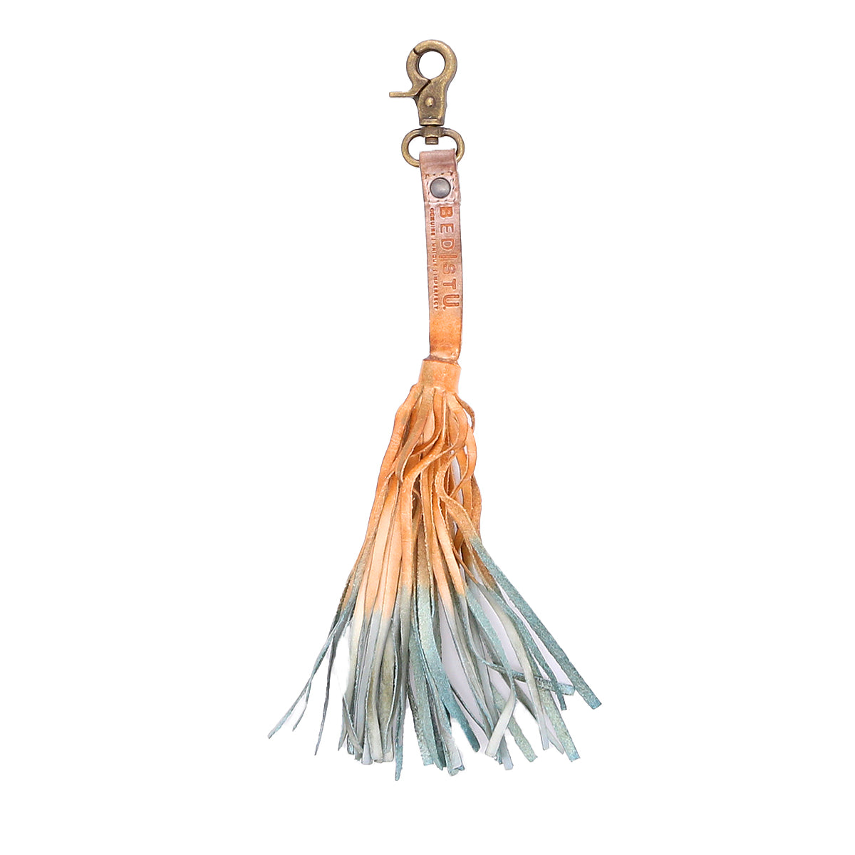 The Bed|Stü Tassel Clip features a leather keychain with a sturdy metal clasp and a long, multicolored fringe in light orange, beige, and blue tones—making it an eye-catching bag accessory or unique keychain charm.