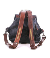 The Teji backpack by Bed|Stü is a black leather bag with two brown leather shoulder straps adorned with stitched leaf patterns, reminiscent of a handwoven leather design, shown from the back against a white background.