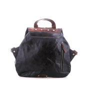 The Teji by Bed|Stü is a black leather backpack featuring brown leather accents, a top handle, zippered front pocket, and visible metal rivets. Blending classic design with the relaxed silhouette of a slouchy shoulder bag, it's displayed on a white background.