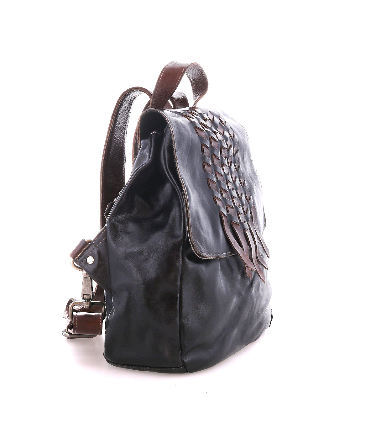 The Bed|Stü Teji backpack features a dark leather body with a handwoven flap design, brown straps, and metal hardware, shown against a white background.
