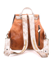 The Teji by Bed|Stü is a brown leather backpack featuring white, textured straps, a back zipper pocket, top handle, and metal hardware. Its slouchy silhouette blends the relaxed style of a shoulder bag. Photographed against a white background.