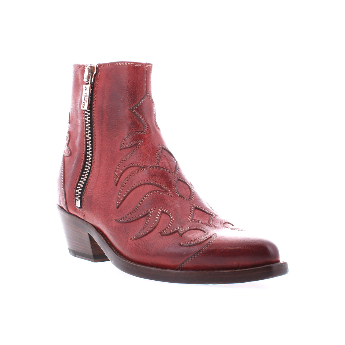 The Tentativa boot by Bed|Stü is a handcrafted Italian red leather ankle boot featuring a side zipper, decorative stitching, stacked heel, and slightly pointed toe, evoking vintage Western charm. It is displayed on a white background.