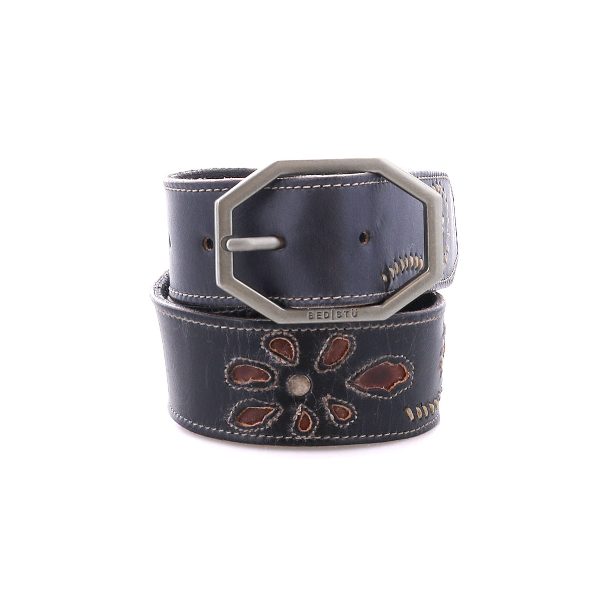 The Upswing II by Bed|Stü is a black handcrafted leather belt, featuring a silver hexagonal buckle and a stitched floral design in brown and cream tones, coiled on a white background.