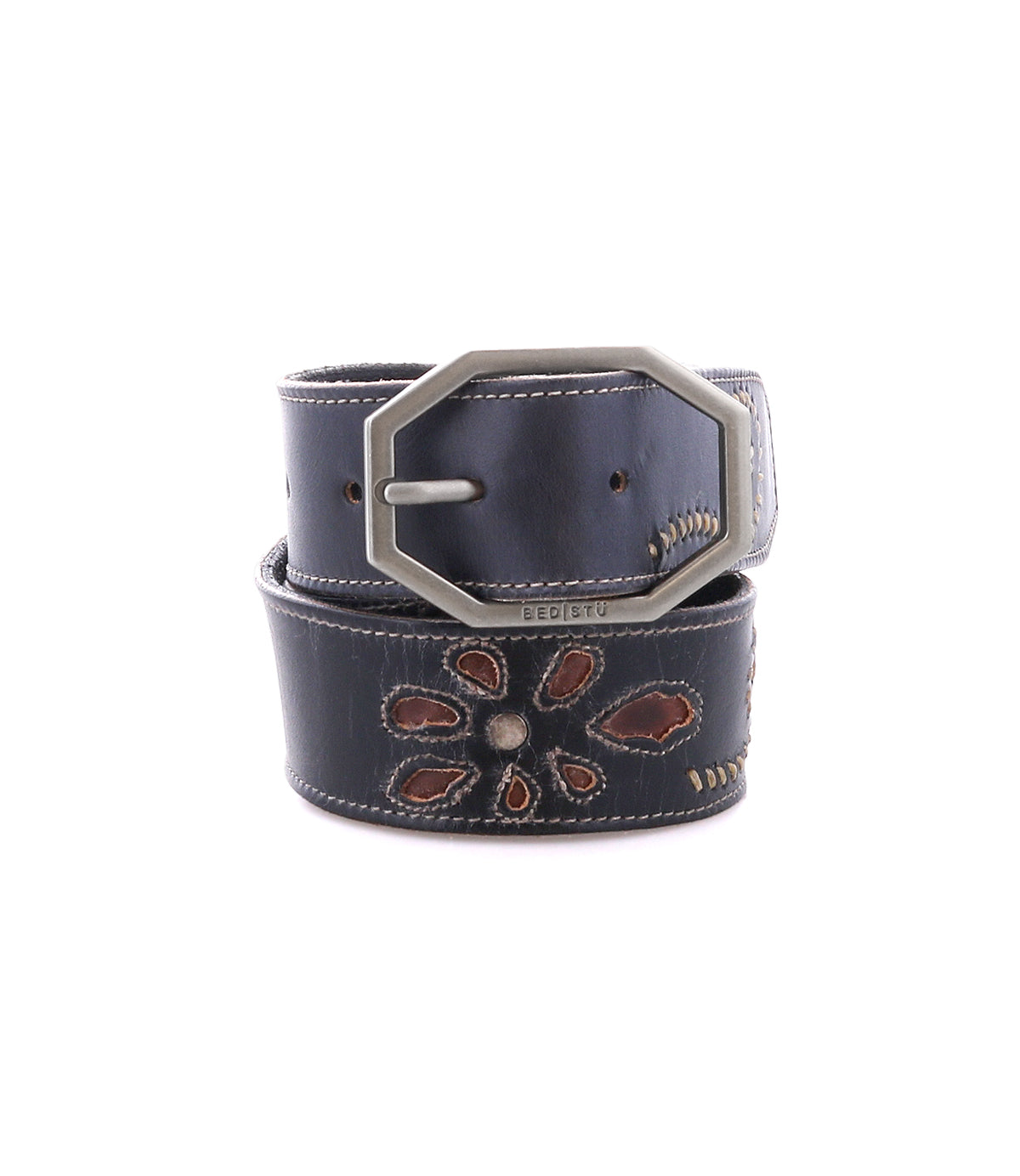 The Upswing II by Bed|Stü is a black handcrafted leather belt, featuring a silver hexagonal buckle and a stitched floral design in brown and cream tones, coiled on a white background.