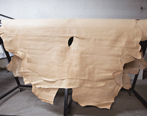 Large pale leather hide draped over a rack in a workshop.
