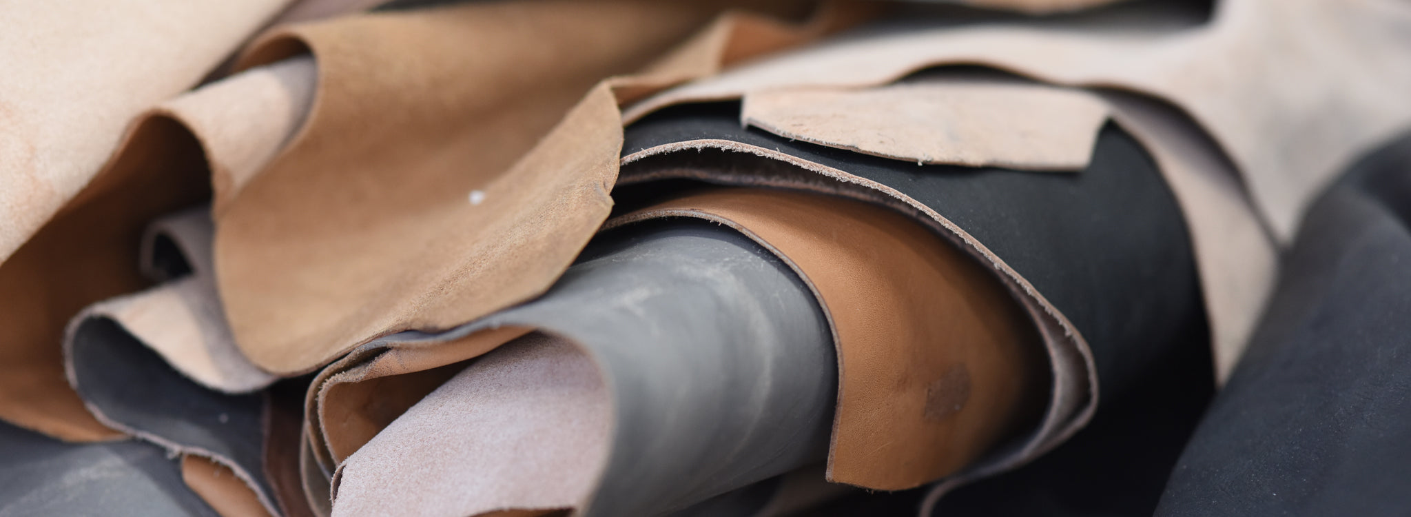 Close-up of assorted leather pieces in tan, brown, gray, and black with raw cut edges.