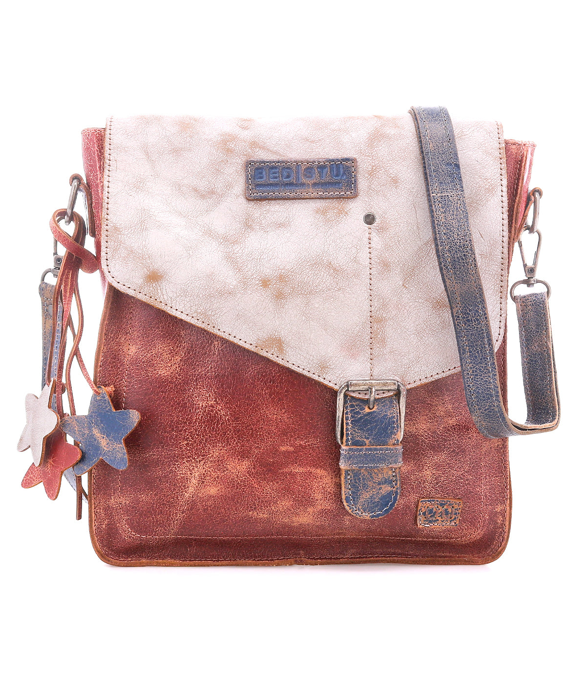 Introducing the Venice Beach crossbody by Bed|Stü—a vintage-inspired bag made from full-grain leather, showcasing a flap closure, buckle detail, star-shaped keychains, and an adjustable strap in distressed red, white, and blue hues.