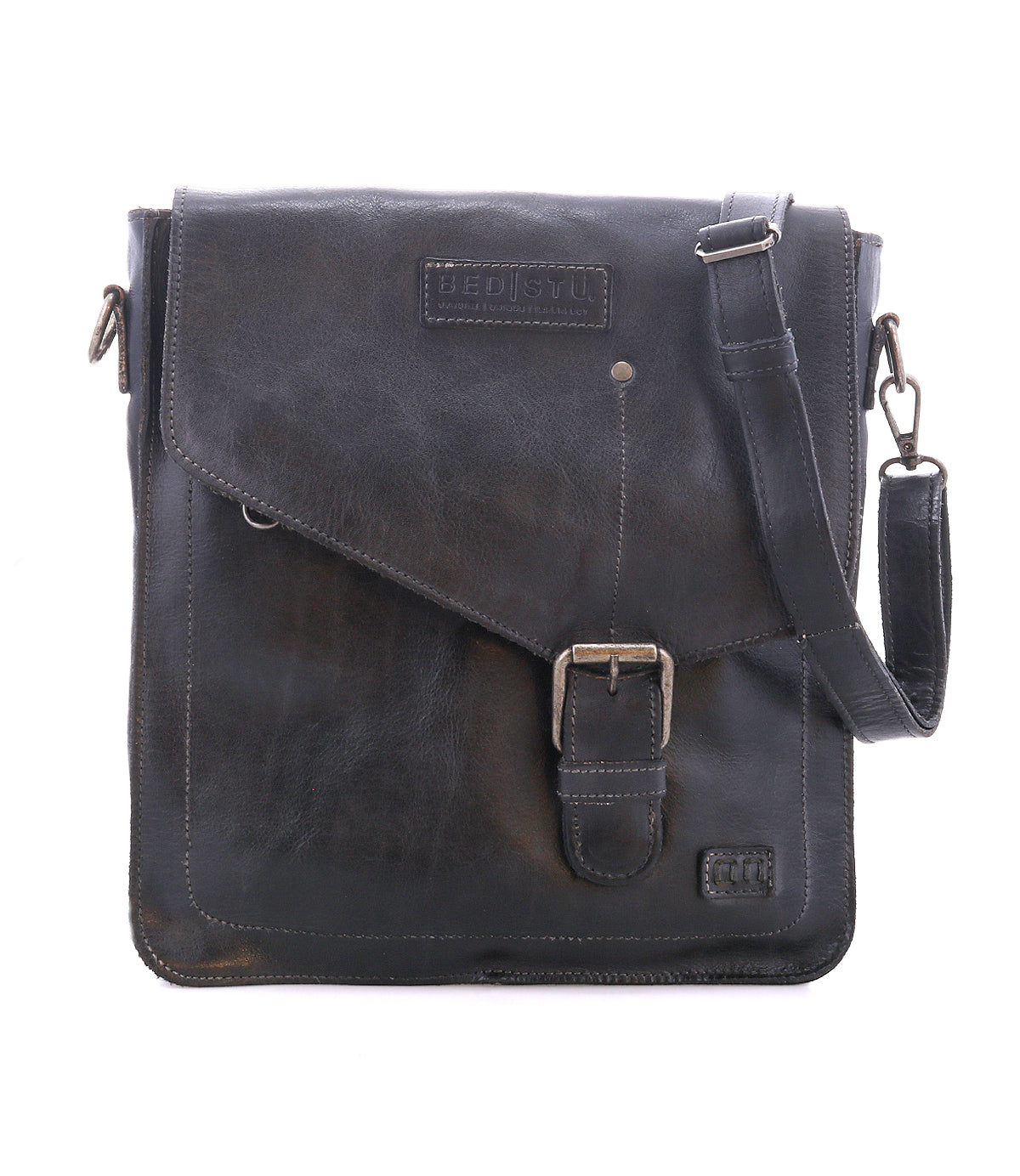 The Bed|Stü Venice Beach messenger bag is crafted from black full-grain leather and features a front buckle, an embossed "BED|STÜ" logo, and an adjustable shoulder strap. Shown against a plain white background, this versatile crossbody bag merges timeless style with practical design.