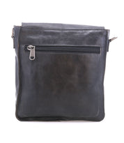 The Bed|Stü Venice Beach is a black full-grain leather shoulder bag featuring a front zippered pocket, displayed against a white background. Designed with an adjustable strap, it can also be worn as a crossbody for versatile styling.