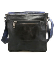 The Venice Beach crossbody bag by Bed|Stü is a square-shaped, black full-grain leather accessory featuring a front zippered pocket and an adjustable blue strap, photographed against a white background.
