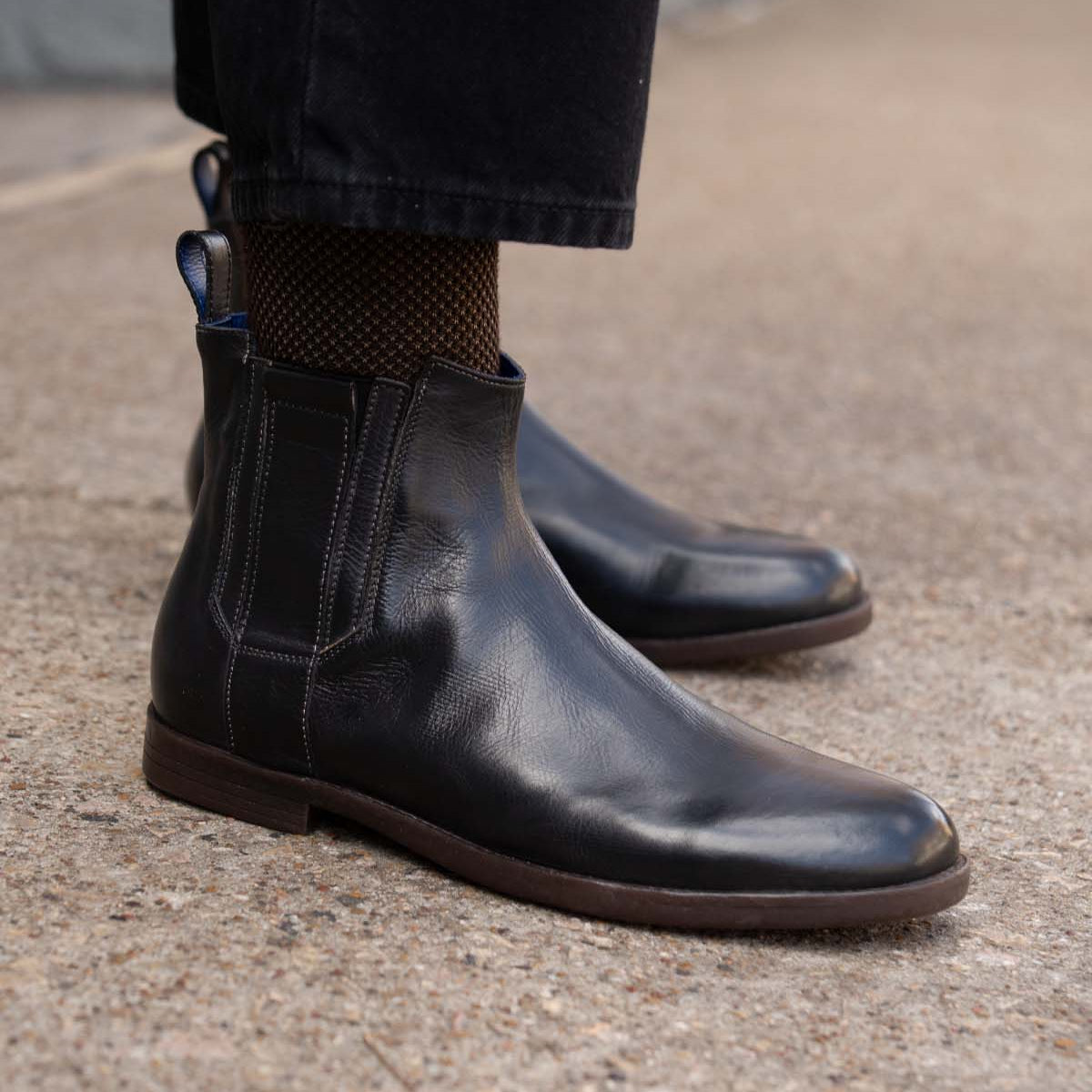 Wearing the Verrocchio handcrafted leather Chelsea boots by Bed|Stü with dark trousers, standing on a concrete surface—perfect for everyday wear.