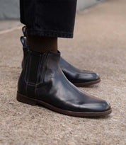 Wearing the Verrocchio handcrafted leather Chelsea boots by Bed|Stü with dark trousers, standing on a concrete surface—perfect for everyday wear.