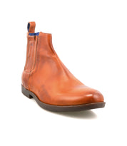 Introducing the Verrocchio by Bed|Stü—a handcrafted leather Chelsea boot in brown, designed for everyday wear. This stylish boot features an elastic side panel, a blue fabric pull tab, and a low black sole, all beautifully displayed on a white background.