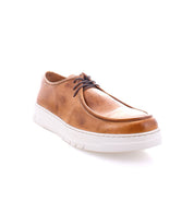 The Bed|Stü Webmaster is a brown leather casual shoe with a lace-up design, showcasing a moc-toe sneaker style, white rubber sole, and dark brown laces; photographed on a white background.