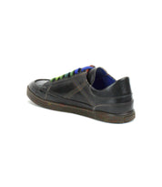 The Bed|Stü Wizard is a black, all-leather casual shoe featuring a low-profile sneaker design, multicolored laces, visible crossover stitching, and a low heel, shown here photographed on a white background.