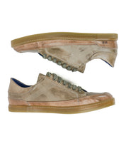 A pair of Bed|Stü Wizard low-top sneakers in tan and brown are displayed side by side on a white background, featuring green laces, gum rubber soles, an all-leather construction, and subtle crossover stitching for added detail.