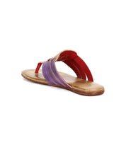 The Bed|Stü Yoli sandal is shown from a rear angled view, featuring a tan sole, purple and red leather straps with visible stitching, and a cushioned insole.