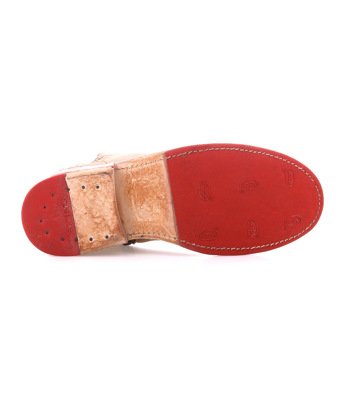 The image shows the bottom of the Bed|Stü Yurisa dress shoe with a tan leather upper and a red rubber sole featuring visible stitching and branding, reminiscent of the meticulous detailing found in a handcrafted boot.