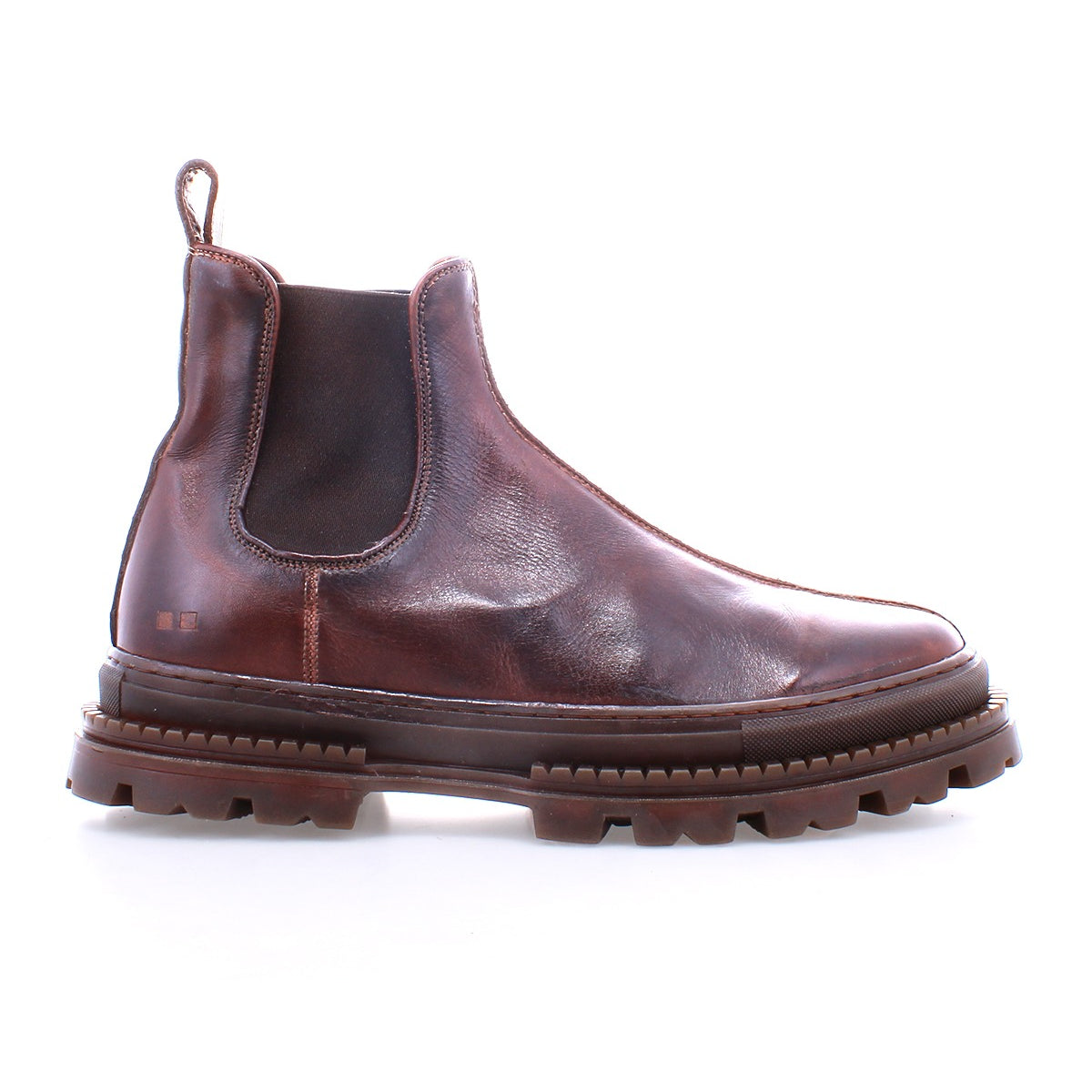 The Bed|Stü Accelerate is a brown leather Chelsea boot featuring elastic side panels, a pull tab, and a thick, rugged lug outsole that adds a modern edge to its classic silhouette, shown on a white background.