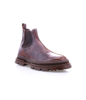 Bed|Stü Accelerate is a brown leather Chelsea boot featuring elastic side panels, a pull tab, and a thick textured lug outsole for a modern edge, shown against a white background.