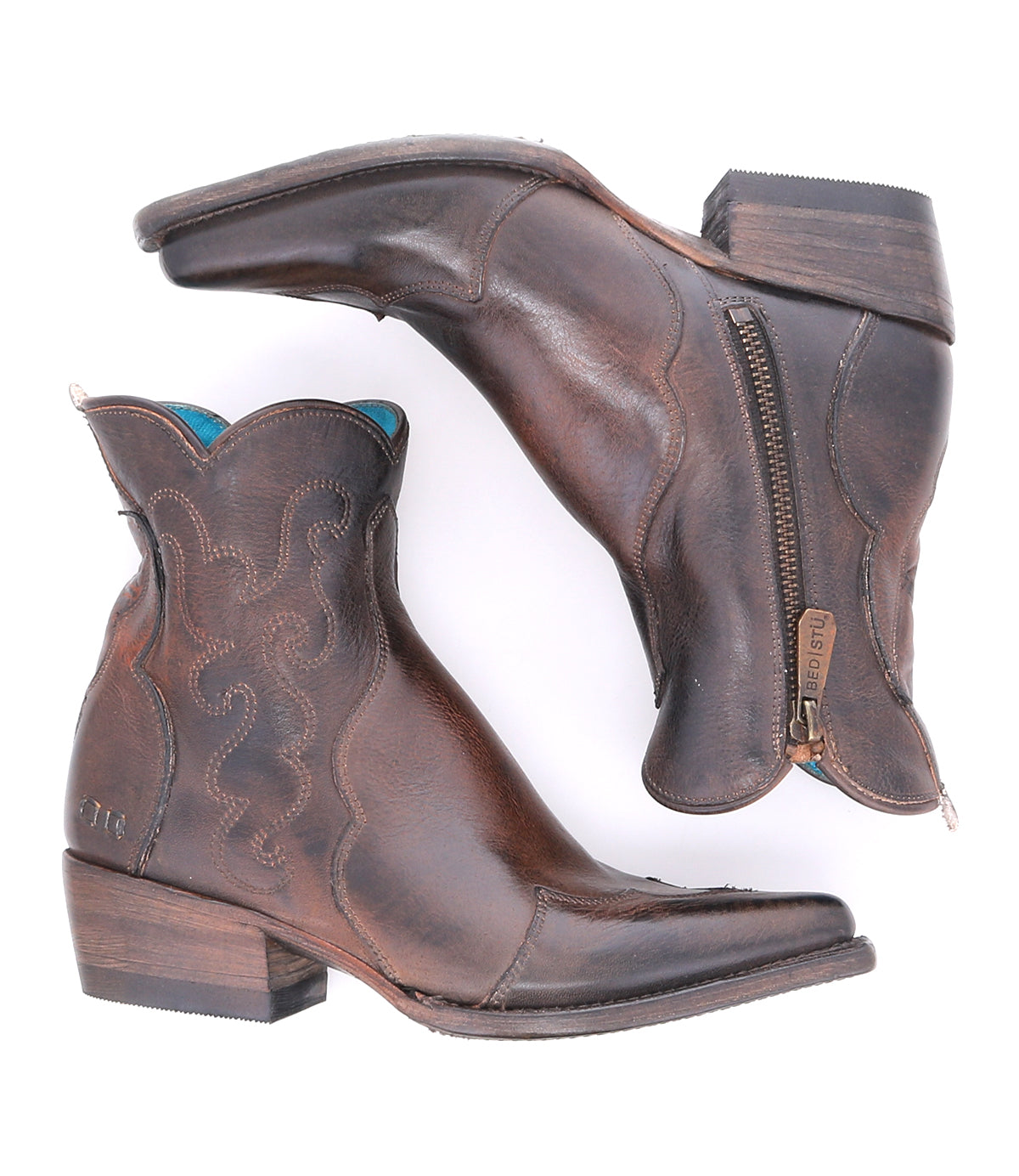 A pair of "Ace" brown full-grain leather ankle cowboy boots by Bed|Stü, featuring decorative stitching, low wooden heels, side zippers, and a slightly pointed toe, inspired by traditional boot making and displayed side by side on a white background.