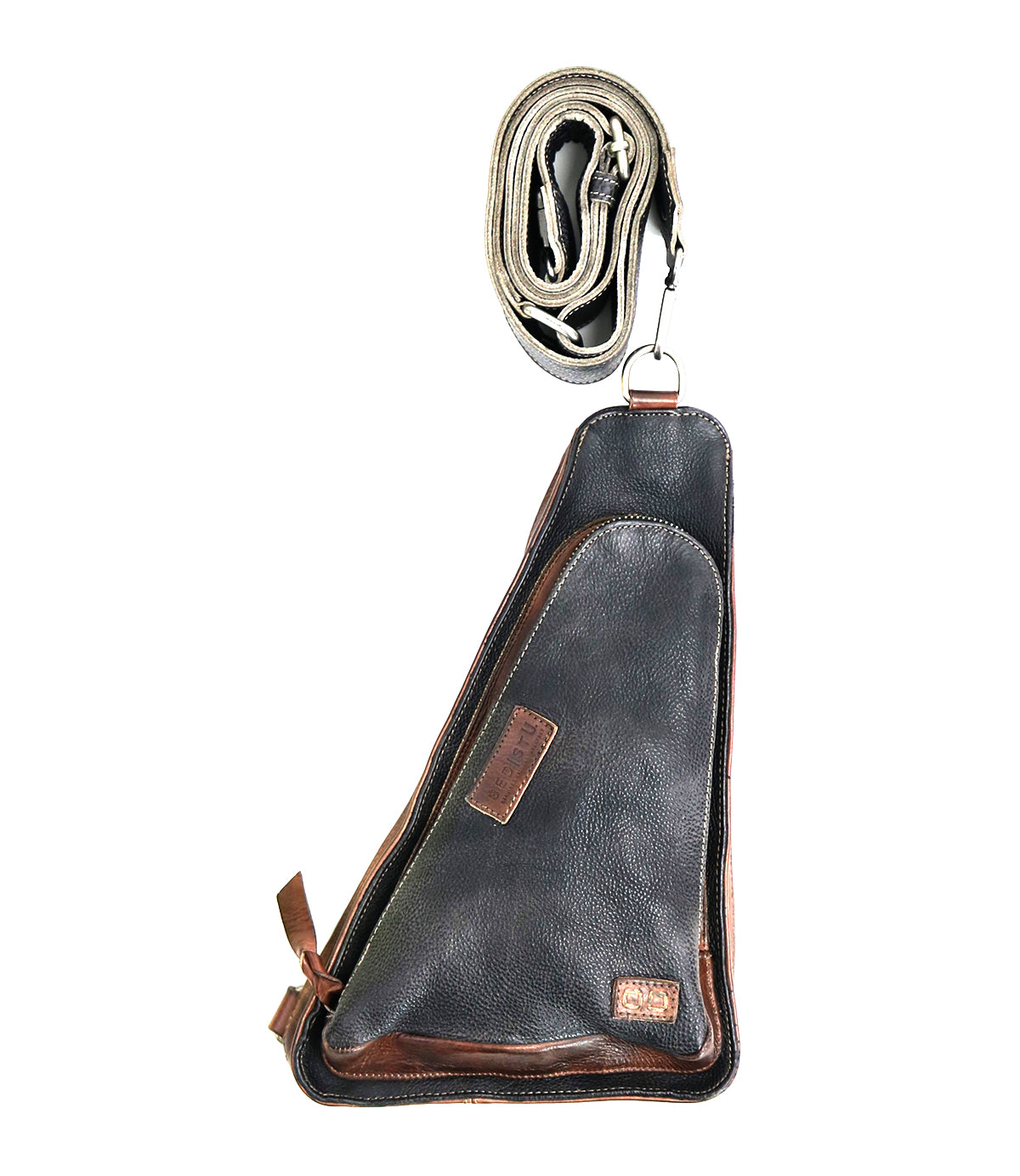 The Bed|Stü Adept is a black and brown compact sling bag crafted from vegetable-tanned leather, featuring a zippered front pocket. It is displayed with its matching adjustable strap rolled up above it.