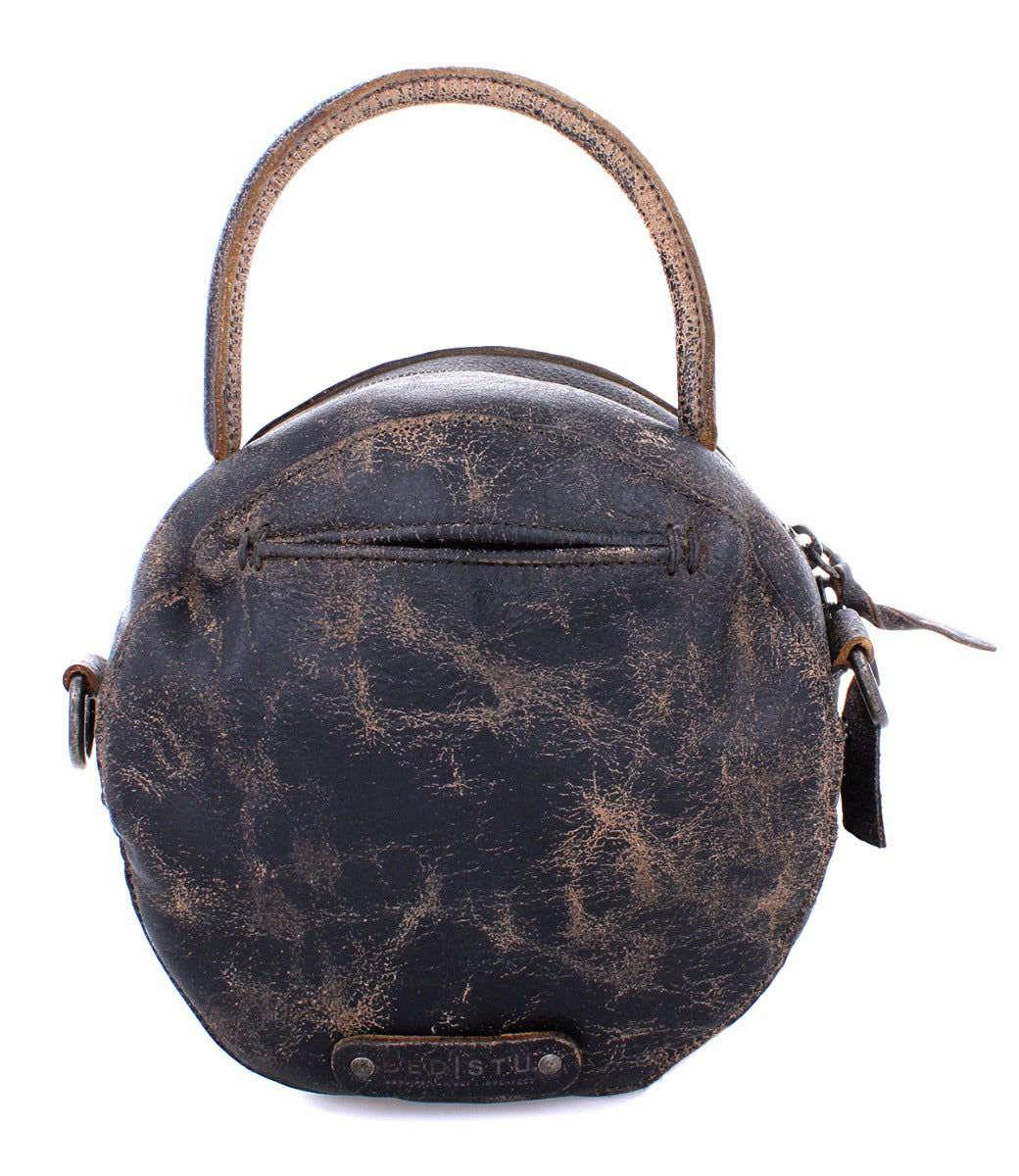 The Arenfield by Bed|Stü is a round, distressed black leather crossbody bag featuring a single top handle, adjustable strap, front zipper pocket, zip-top closure, and a branded label at the bottom.