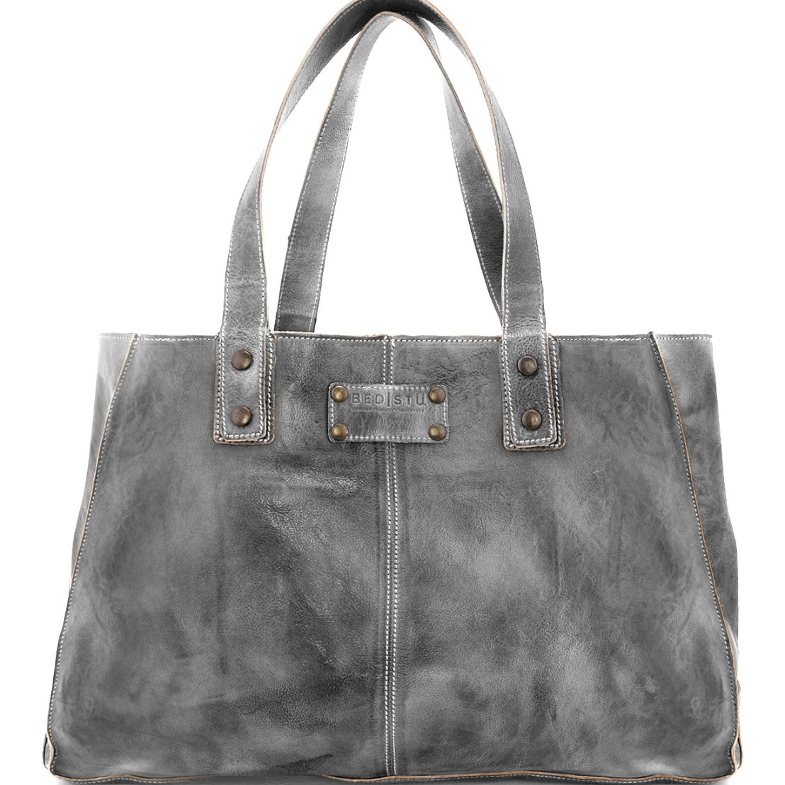 The Arlington by Bed|Stü is a gray leather tote bag featuring double handles, metal rivets, visible stitching, and a small rectangular brand label on the front—a distinctive design crafted to stand out. Ideal as a custom bag for those who value both style and individuality.