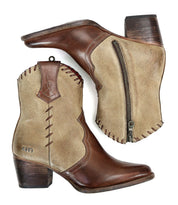 Introducing the Baila II by Bed|Stü: a pair of two-tone leather ankle boots crafted with artisanal precision. Featuring brown toes and heels contrasted by tan sides, decorative stitching, and practical side zippers, these Western-inspired boots—shown from both a side and bottom angle—are finished with refined detailing for a truly distinctive look.