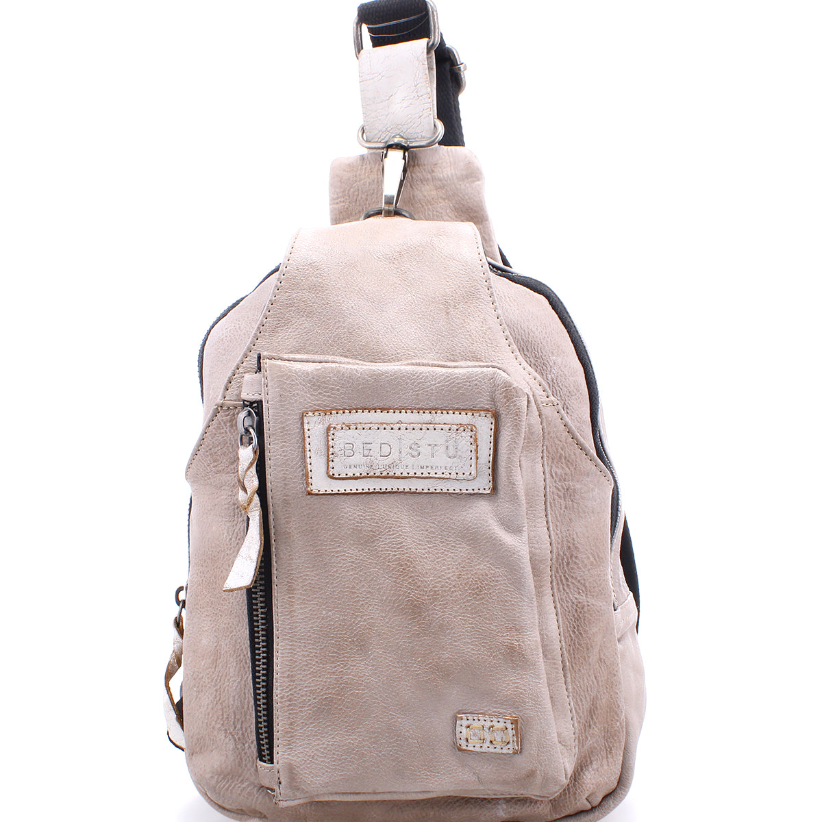 Beau by Bed|Stü is a beige leather sling bag featuring a front zippered pocket, stitched logo patch, top handle, and adjustable shoulder strap—perfect as a stylish and compact backpack for your everyday essentials.