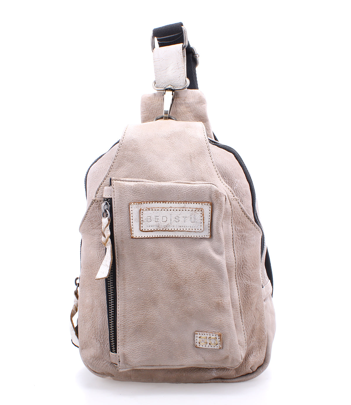 Beau by Bed|Stü is a beige leather sling bag featuring a front zippered pocket, stitched logo patch, top handle, and adjustable shoulder strap—perfect as a stylish and compact backpack for your everyday essentials.