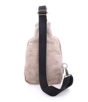 The Beau backpack by Bed|Stü is shown from the back in beige suede, featuring a black adjustable shoulder strap and silver hardware, set against a white background.