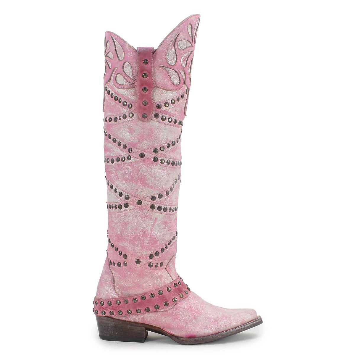 The Bed|Stü Betting is a tall pink cowboy boot featuring decorative stitching, studded harness details, and a pointed toe. Handcrafted from premium leather, it is displayed on a white background.