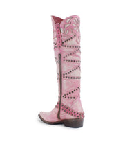 The Bed|Stü Betting is a tall pink cowboy boot with decorative stitching, metal studs, and a side zipper, featuring intricate floral inlays. It is shown from a side view on a white background.