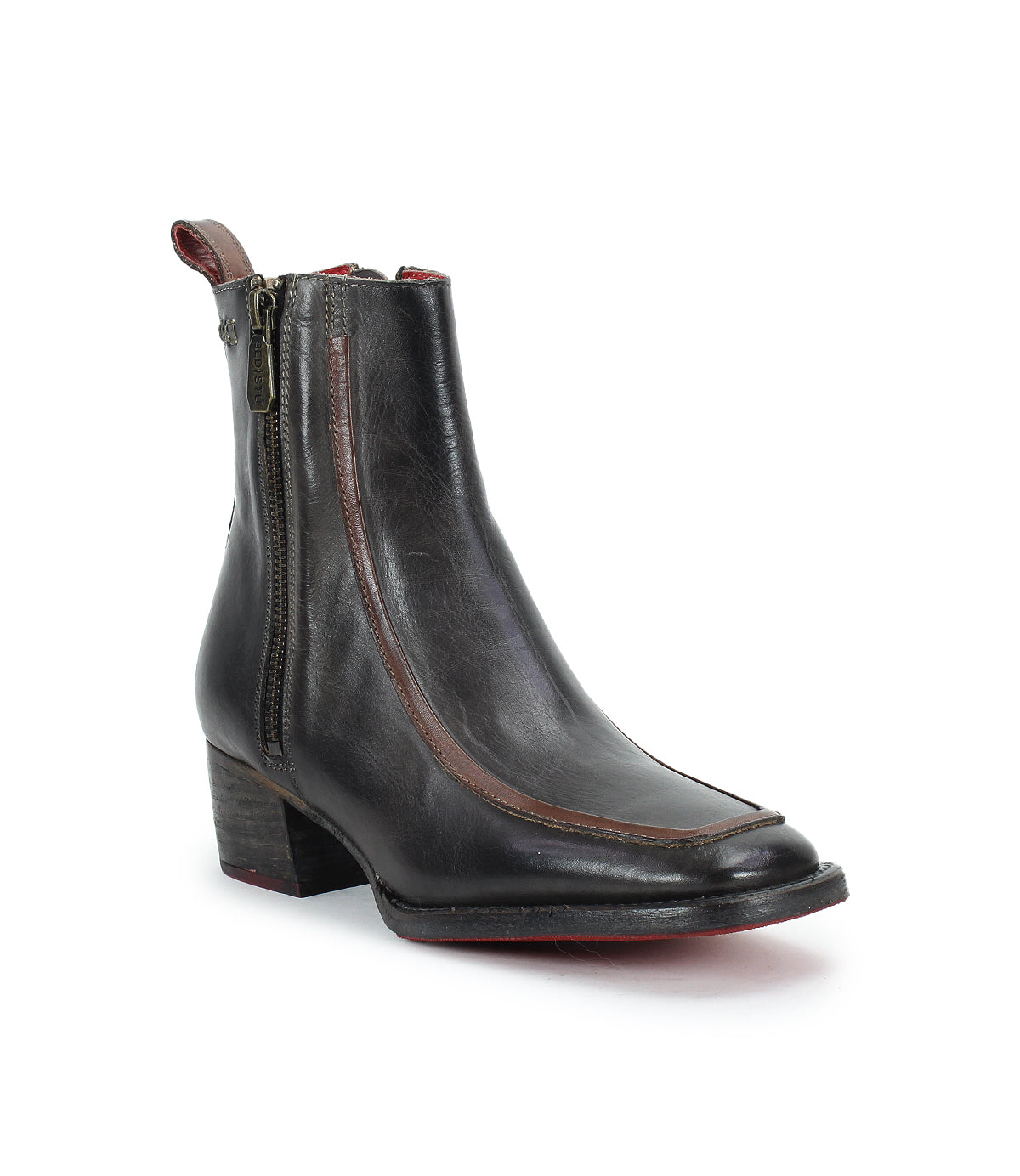 The Bed|Stü Bitsy is a black leather ankle boot featuring a side zipper, low stacked heel, and subtle brown trim accents. Showcased on a white background, these stylish boots combine timeless appeal with a modern silhouette for an effortlessly classic look.