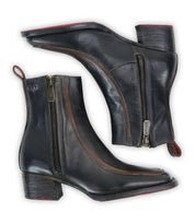 A pair of Bed|Stü "Bitsy" black leather ankle boots with brown accents, side zippers, low stacked heels, and red pull tabs, displayed from the side against a white background.